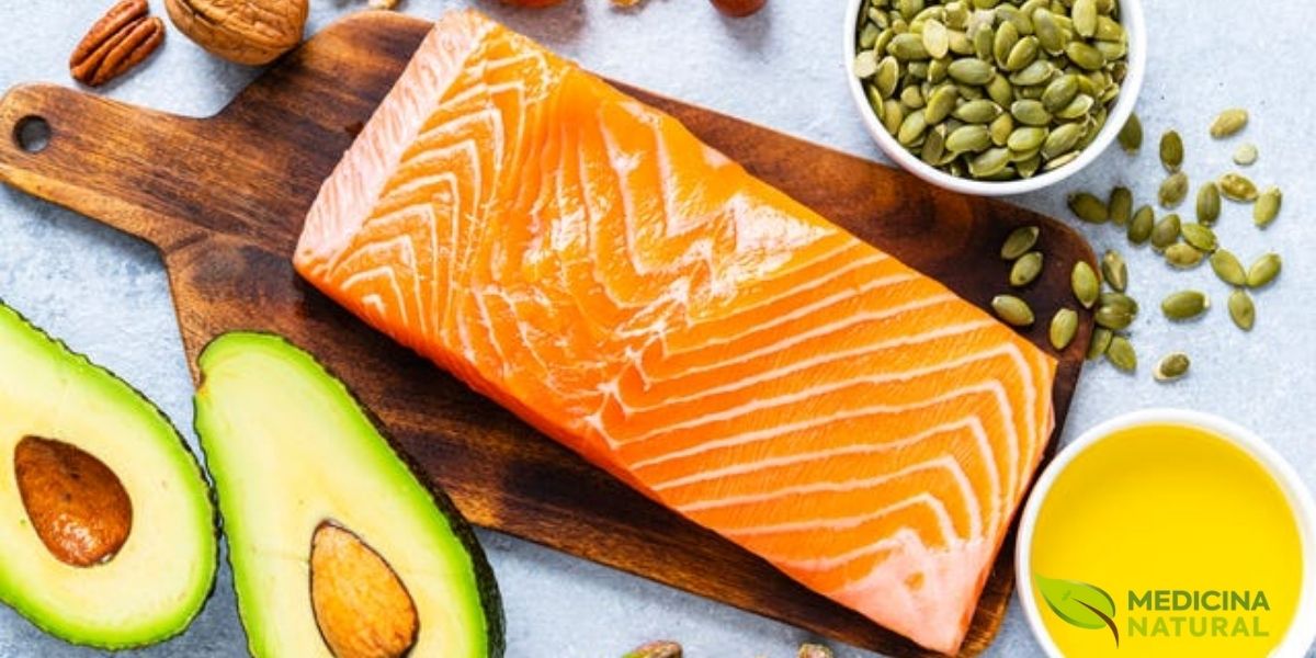 Composição harmoniosa de alimentos ricos em gorduras boas: salmão fresco, abacate cortado ao meio, variedade de oleaginosas (nozes, amêndoas, pistache), sementes de abóbora em tigela de madeira e azeite de oliva em pequeno recipiente. Dispostos sobre superfície clara, representando as principais fontes de ácidos graxos insaturados essenciais para saúde cardiovascular e cerebral. Composição harmoniosa de alimentos ricos em gorduras boas: salmão fresco, abacate cortado ao meio, variedade de oleaginosas (nozes, amêndoas, pistache), sementes de abóbora em tigela de madeira e azeite de oliva em pequeno recipiente. Dispostos sobre superfície clara, representando as principais fontes de ácidos graxos insaturados essenciais para saúde cardiovascular e cerebral.