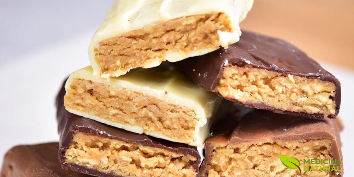 Barras de proteína caseiras com cobertura de chocolate meio amargo e recheio cremoso de pasta de amendoim natural, empilhadas de forma atraente para revelar as camadas internas. Esta imagem demonstra que barras de proteína saudáveis não precisam sacrificar o sabor, combinando o prazer do chocolate com os benefícios nutricionais da pasta de amendoim integral, rica em proteínas vegetais e gorduras monoinsaturadas.