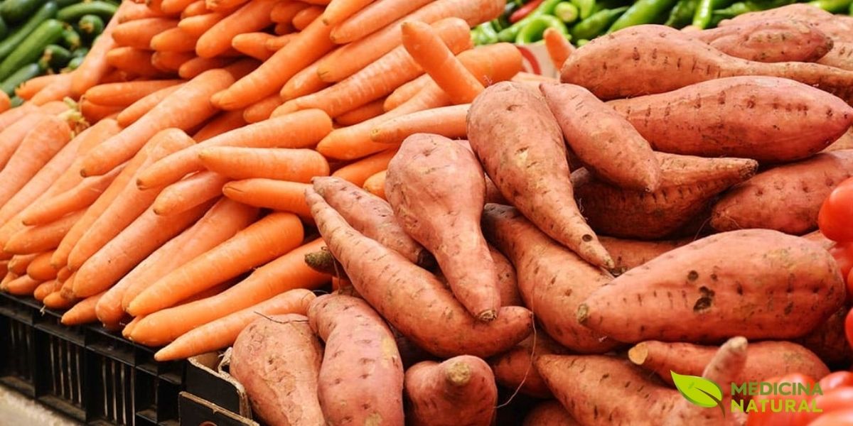 Batata-doce e cenoura lado a lado, duas das fontes vegetais mais potentes de vitamina A. A batata-doce de polpa alaranjada pode fornecer mais de 100% da necessidade diária de vitamina A em uma única porção, enquanto a cenoura, famosa por seus benefícios para a visão, oferece uma dose robusta de betacaroteno que o corpo converte eficientemente em retinol.