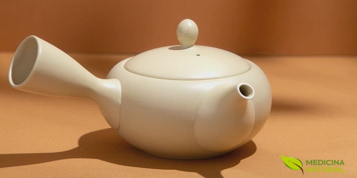 Bule Kyusu japonês tradicional em cerâmica bege com alça lateral característica, o utensílio por excelência para preparar chá verde japonês como Sencha e Gyokuro. Seu design ergonômico permite servir com um movimento gracioso do pulso, enquanto o filtro de cerâmica embutido retém perfeitamente as folhas delicadas sem interferir no sabor. Este tipo de bule é essencial para extrair o máximo de doçura e umami dos chás verdes japoneses de alta qualidade.