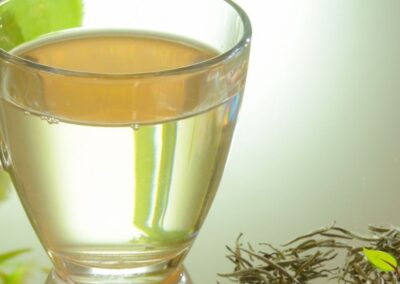 Preparação tradicional do chá branco com bule e xícara, demonstrando a técnica correta de infusão. Use água entre 75-85°C e infusão de 3-5 minutos para extrair sabor delicado sem amargor. O preparo adequado preserva os compostos bioativos e permite múltiplas infusões das mesmas folhas.