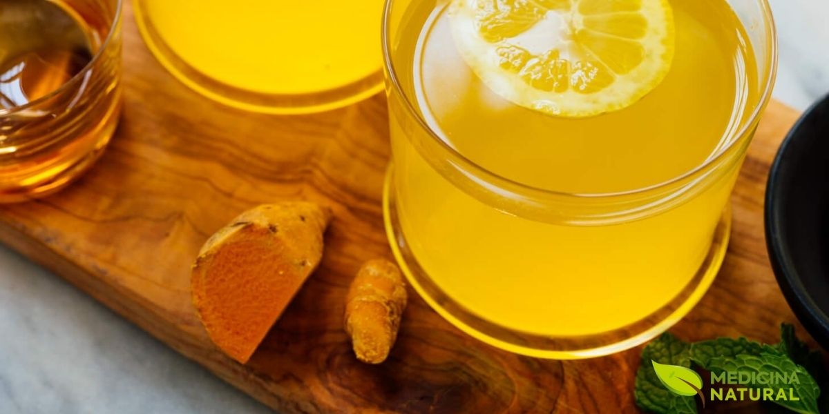 Copo de vidro transparente com chá de cúrcuma dourado, permitindo visualizar a cor vibrante característica da bebida. A transparência revela a intensidade da infusão, indicando alta concentração de curcuminoides. Esta apresentação é ideal para apreciar visualmente a qualidade da bebida antes do consumo.