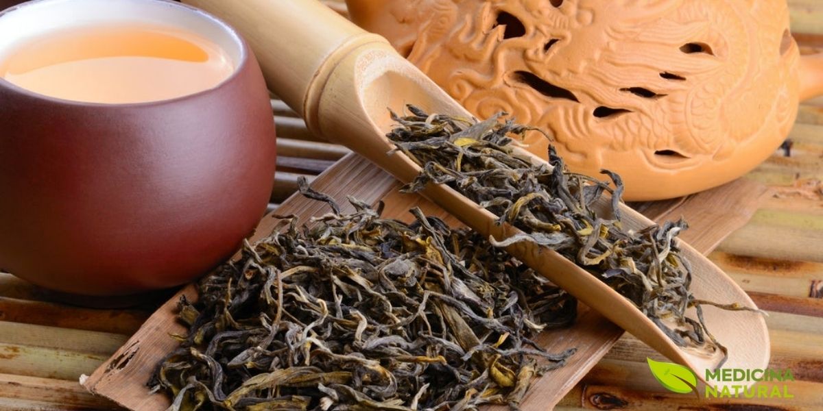 O chá oolong representa o fascinante meio-termo entre o chá verde e o chá preto na escala de oxidação. As folhas de oolong, visíveis na imagem com sua coloração que varia do verde ao marrom, passam por um processo de oxidação parcial controlada, que pode variar de 10% a 80%, dependendo do estilo desejado. Este processo confere ao oolong uma complexidade de sabor única, combinando as notas frescas e vegetais do chá verde com as características maltadas e frutadas do chá preto.