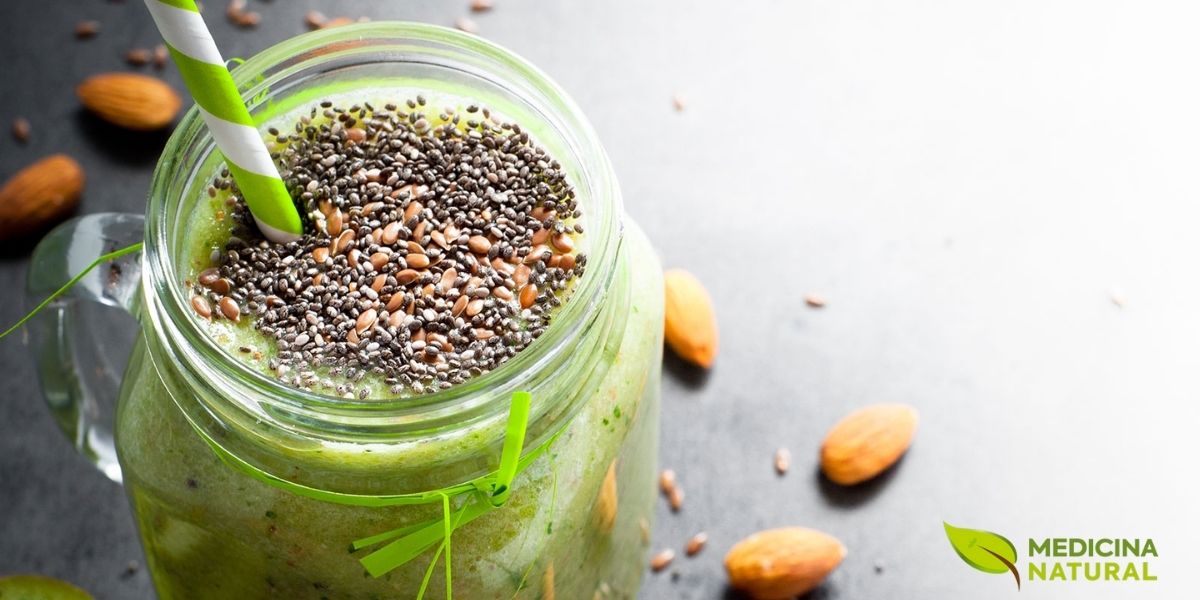 Pote de vidro com smoothie verde decorado com sementes de chia e linhaça. Estas sementes são as melhores fontes vegetais de ômega 3 (ALA), que o corpo converte parcialmente em EPA e DHA. Uma colher de sopa de linhaça moída fornece cerca de 2,4g de ômega 3.