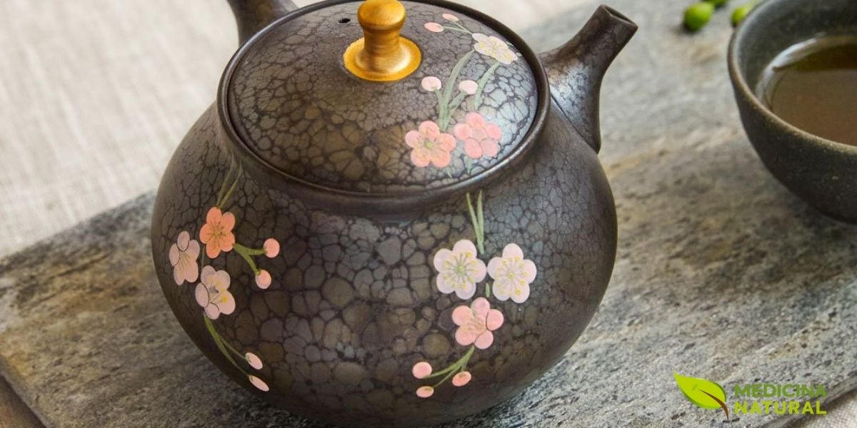 Kyusu em cerâmica preta com delicada decoração floral em relevo e acabamento artesanal, exemplo da sofisticada arte ceramista japonesa aplicada aos utensílios para cerimônia do chá verde. As flores de cerejeira (sakura) esculpidas na superfície representam a estética wabi-sabi e a conexão com a natureza que permeia a cultura do chá no Japão. Este tipo de bule combina funcionalidade técnica com beleza contemplativa, transformando o preparo do chá em uma experiência estética completa.