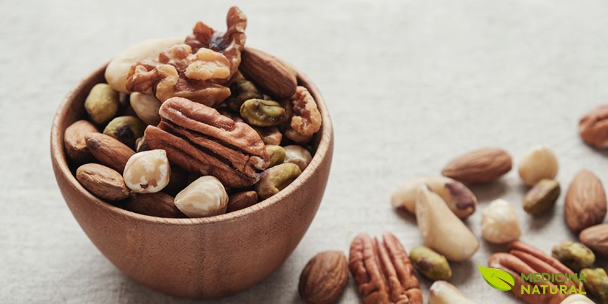 Tigela de cerâmica contendo mix variado de oleaginosas: nozes, amêndoas, castanhas e avelãs. Este mix fornece perfil completo de gorduras saudáveis, proteínas vegetais, fibras e antioxidantes. Consumir variedade de oleaginosas é melhor que focar em apenas uma, pois cada tipo oferece nutrientes únicos.