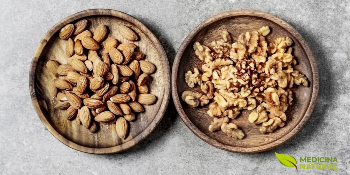 Tigelas de madeira contendo nozes e amêndoas, duas das oleaginosas mais saudáveis. As nozes são ricas em ômega 3 (ALA), enquanto as amêndoas fornecem principalmente ômega 9 e vitamina E. Ambas ajudam a reduzir colesterol LDL, controlar glicemia e promover saciedade. Um punhado diário (30g) é recomendado para saúde cardiovascular.