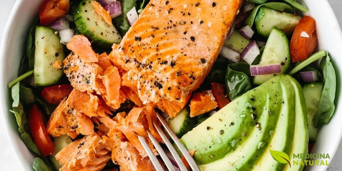 Salada vibrante e nutritiva combinando folhas verdes frescas, tomates-cereja, salmão grelhado em cubos, fatias de abacate maduro, pepino e molho leve. Prato completo que exemplifica refeição rica em gorduras boas: ômega 3 do salmão (EPA e DHA), ômega 9 do abacate, fibras e antioxidantes dos vegetais. Ideal para saúde cardiovascular, saciedade prolongada e controle glicêmico, demonstrando como gorduras saudáveis tornam refeições mais saborosas e nutritivas.